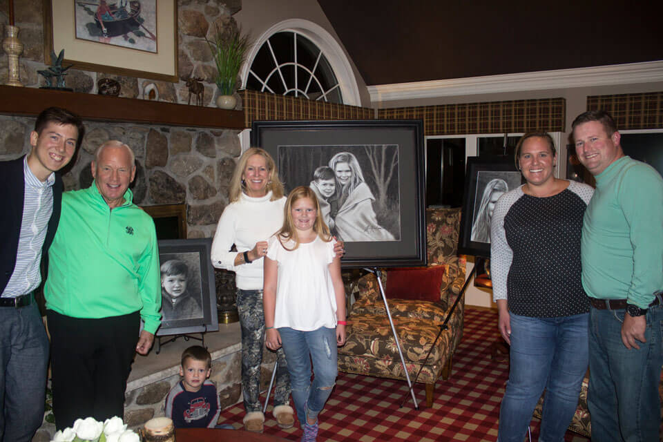 A family with Jon Kardamis at the unveiling of their three commissioned charcoal pieces